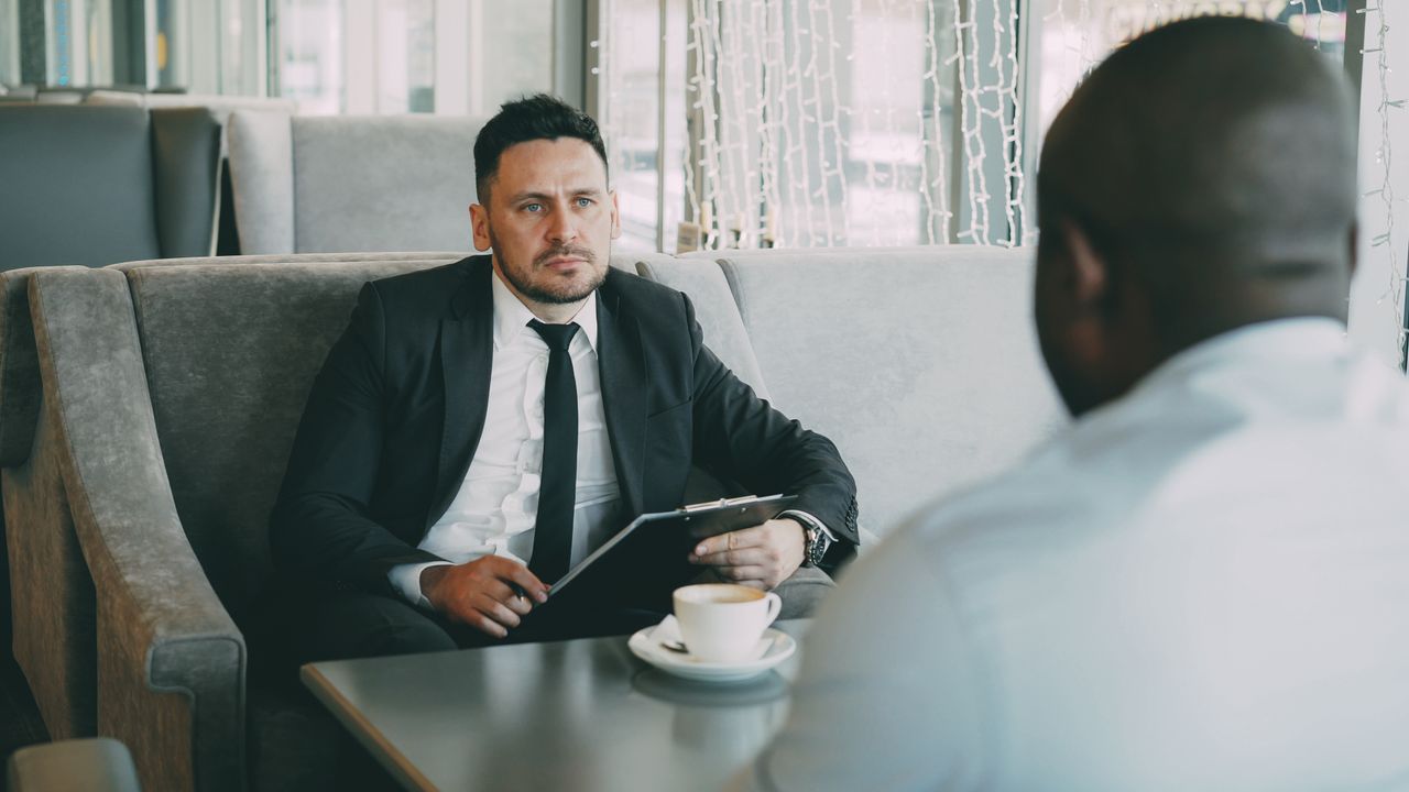 Two businessmen having a serious conversation over coffee in a stylish cafe setting.